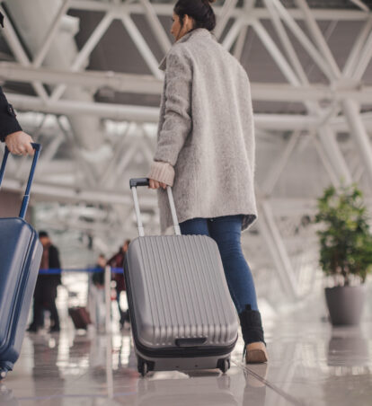 Young couple arriving at the airport, pulling a suitcases