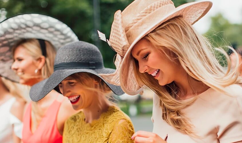 Three women in Kentucky Derby hats laughing