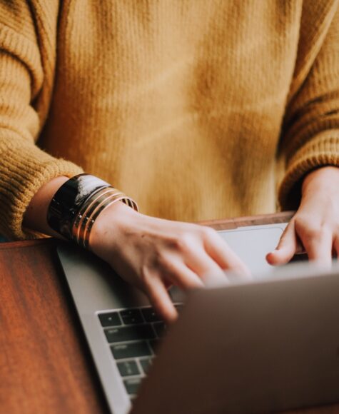 woman in yellow sweater working on macbook