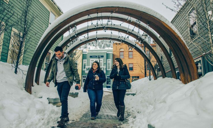 Three people walking under snow-covered arches