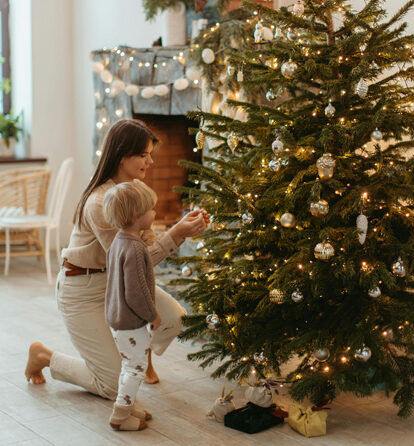 a woman and a child decorating a Christmas tree