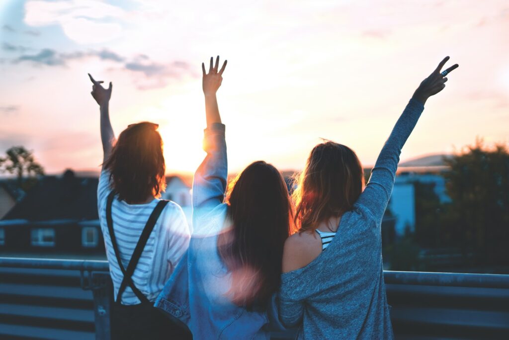 Three people standing on the side of a road facing a sunset